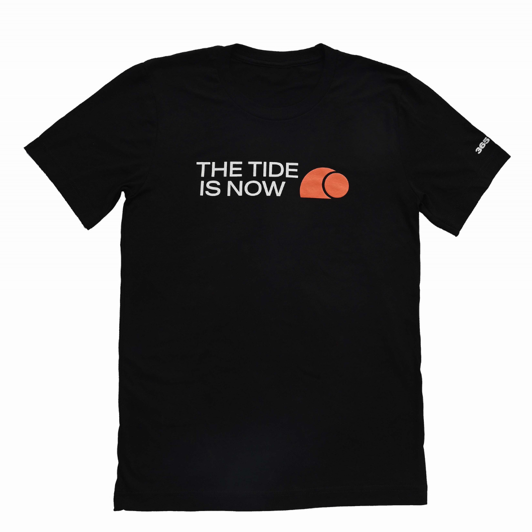 A black tshirt with The Tide Is Now written on it in white with an orange logo