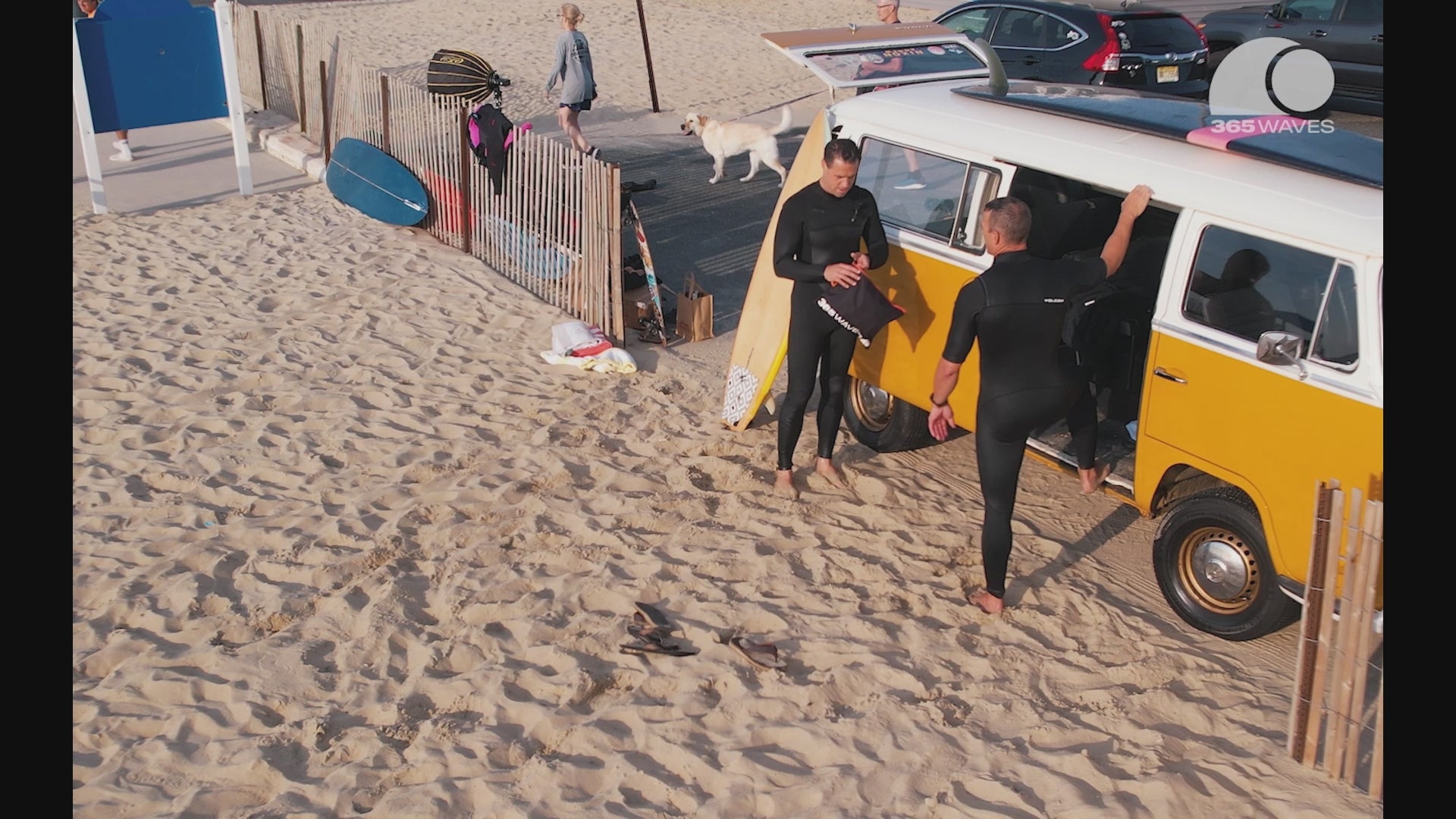 A video of two men using the Changing Mat/Dry Bag on a sandy beach to keep a yellow VW van dry from their wetsuits